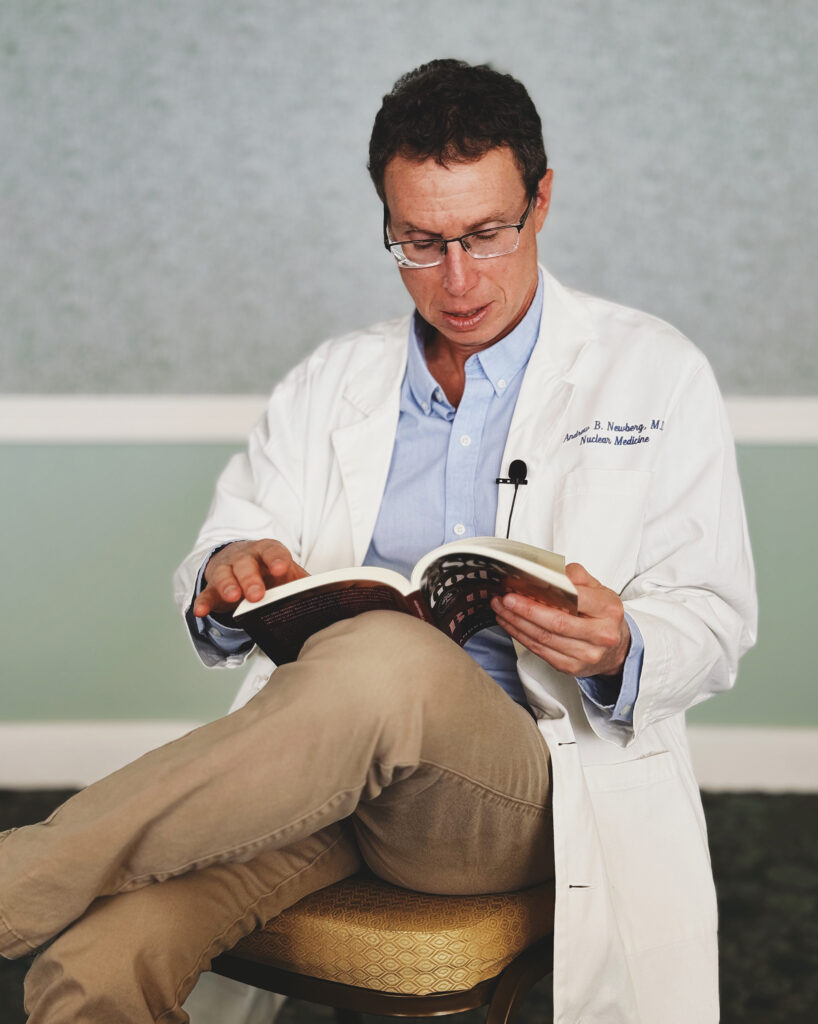 Dr. Newberg, in a white coat, reading a human sexuality book titled "Sex, God and the Brain."